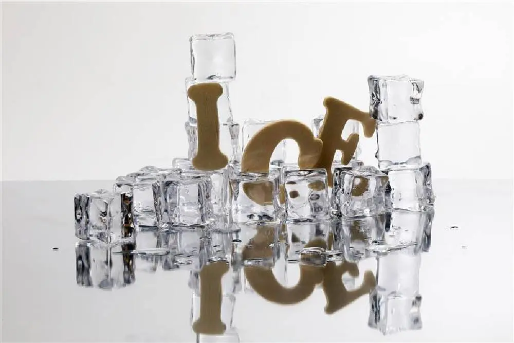 A pile of clear, cubed ice slowly melts, one of the many different types of ice that can affect your beverages. The word “Ice” falls as the pile of cubes melt.