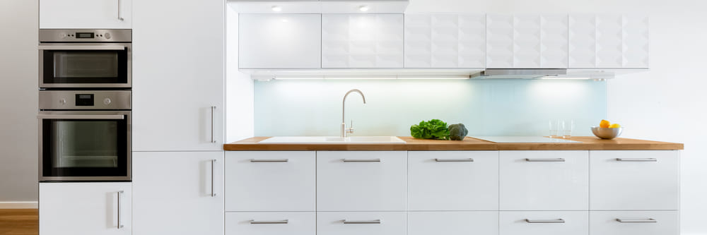 A beautifully modern, white kitchen, showcasing an in-cabinet oven and microwave drawer above, with a nice, clean empty wooden countertop being showcased A beautifully modern, white kitchen, showcasing an in-cabinet oven and microwave drawer above, with a nice, clean empty wooden countertop being showcased