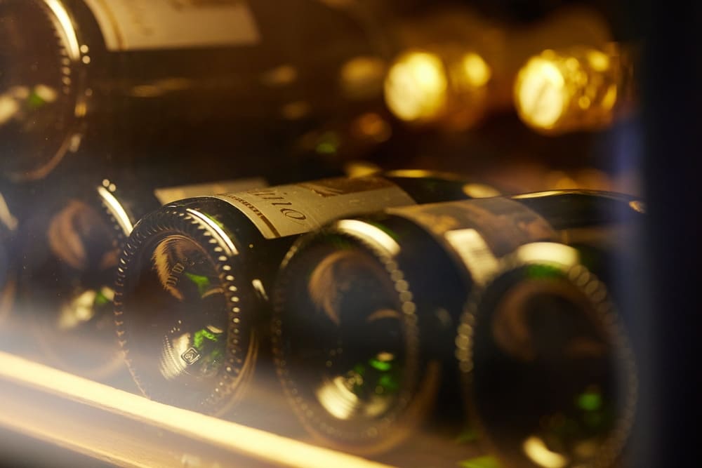 A view of wine bottles being kept at the best temperature within a wine refrigerator.
