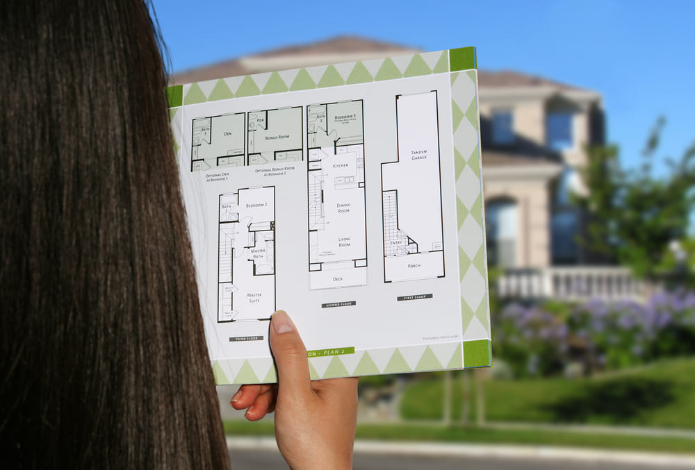 A woman considers the floor plan to her home, wondering how much does an outdoor kitchen costs to build in her backyard A woman considers the floor plan to her home, wondering how much does an outdoor kitchen costs to build in her backyard.