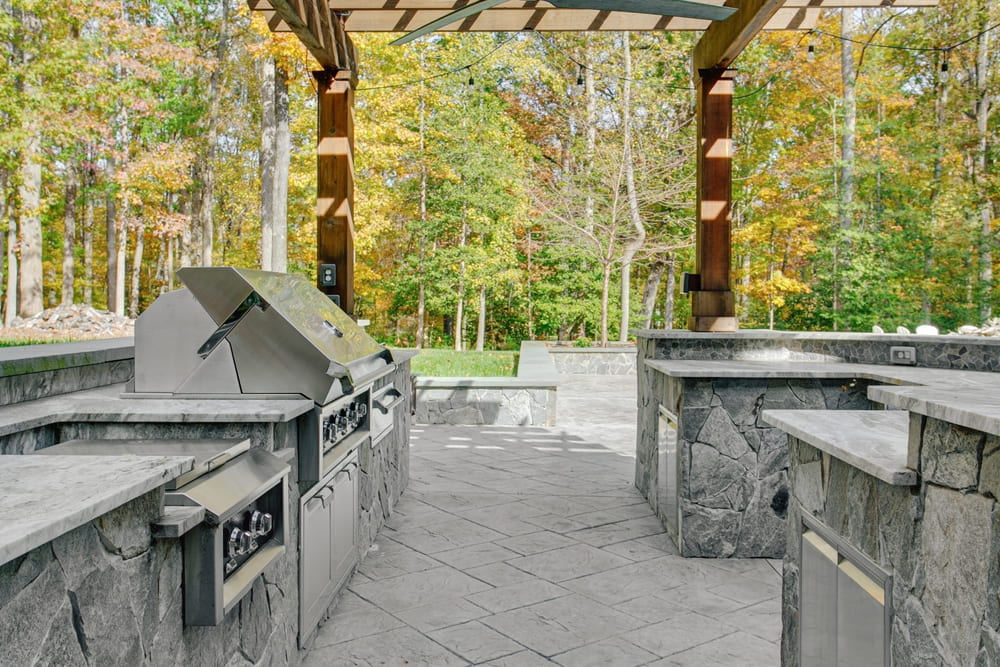 After wondering how much an outdoor kitchen costs, a happy homeowner showcases their new outdoor kitchen space with stone and stainless steel.