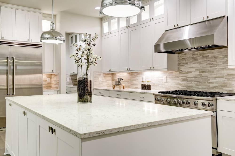 A gourmet luxury kitchen featuring white shaker cabinets and a kitchen island design that blends integrated under-counter XO appliances cleverly hidden.