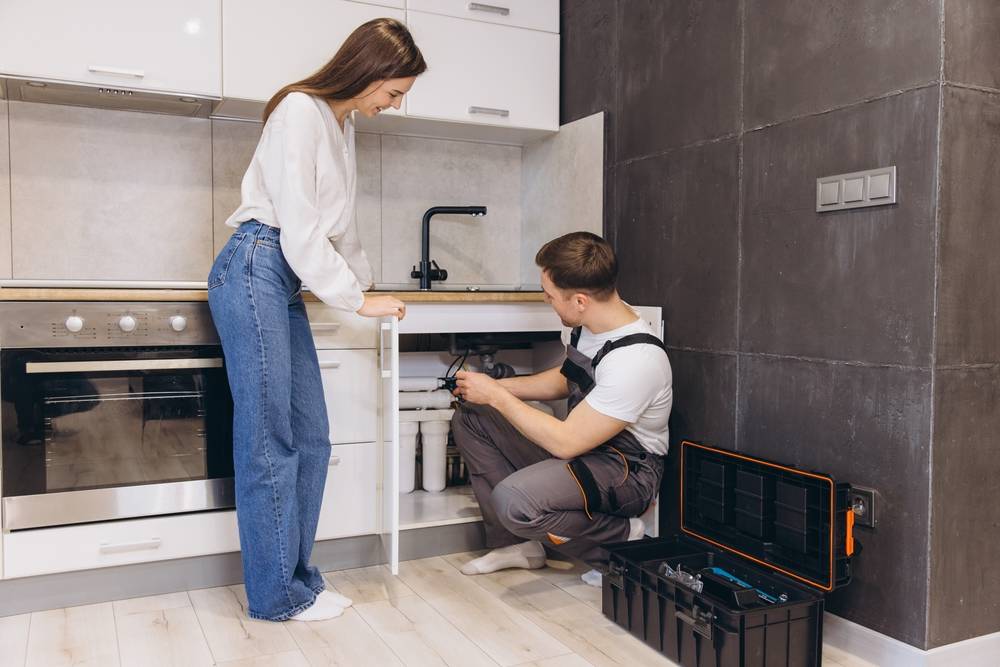 A professional plumber assists in an evaluation for an XO customer looking to install her new water filter system for the home.